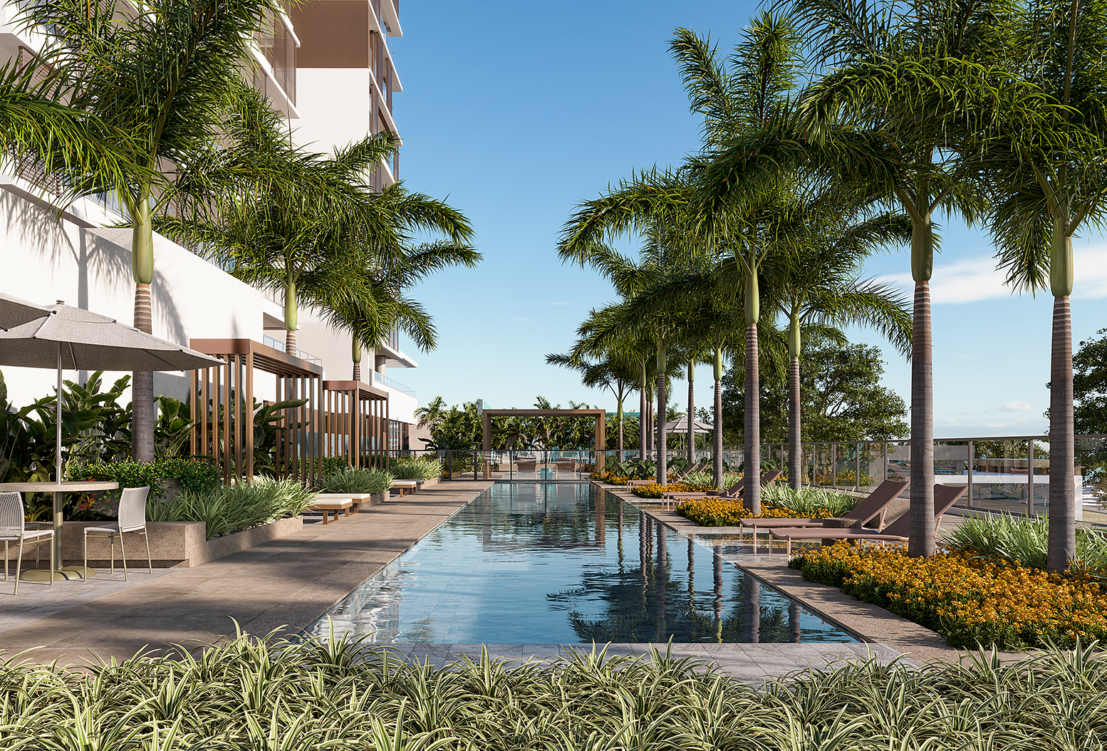 Área de lazer com piscina, palmeiras, espreguiçadeiras e mesas com guarda-sóis ao lado do prédio.