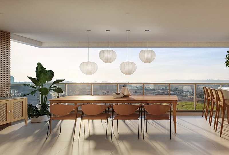 Varanda gourmet ampla, com mesa, bancada com banquetas, churrasqueira e vista aberta ao pôr do sol.