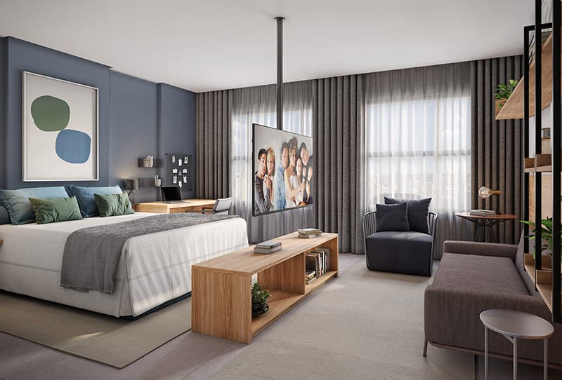 Studio integrado com cama, sofá, TV e cozinha ao fundo, em ambiente moderno com acabamentos em madeira.