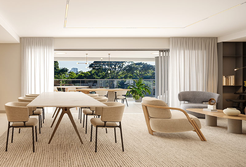 Sala integrada com cozinha americana, bancada com banquetas, mesa de jantar, estar com poltronas e varanda arborizada.